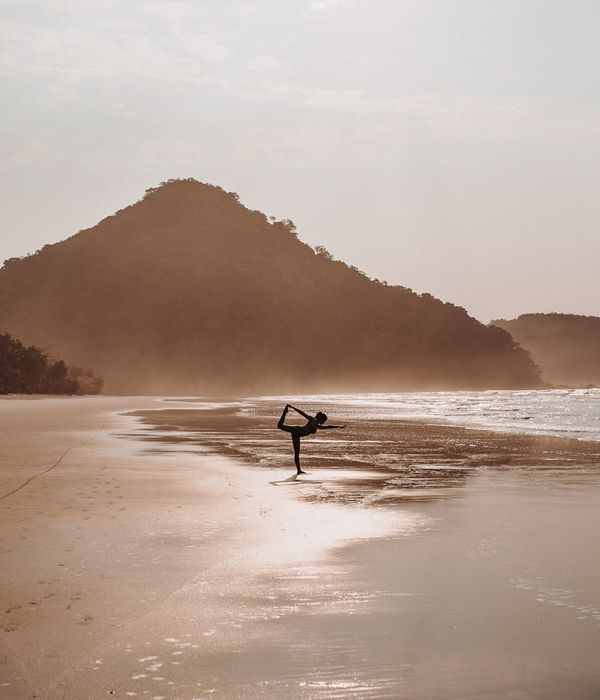 Woman in a peaceful yoga pose during sunrise with blue light accents.